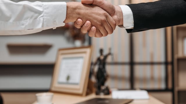 A close-up of two people shaking hands, representing a successful lending partnership